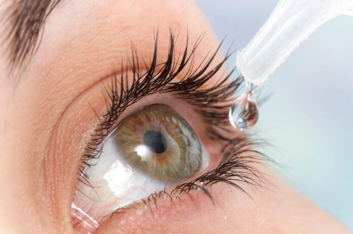 WOMAN USING EYE LOTION
